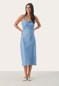 Rochie midi de culoare albastru deschis, cu bretele subțiri, țesătură texturată, decolteu pătrat și ușor în formă de A, asortată cu pantofi plata argintii.