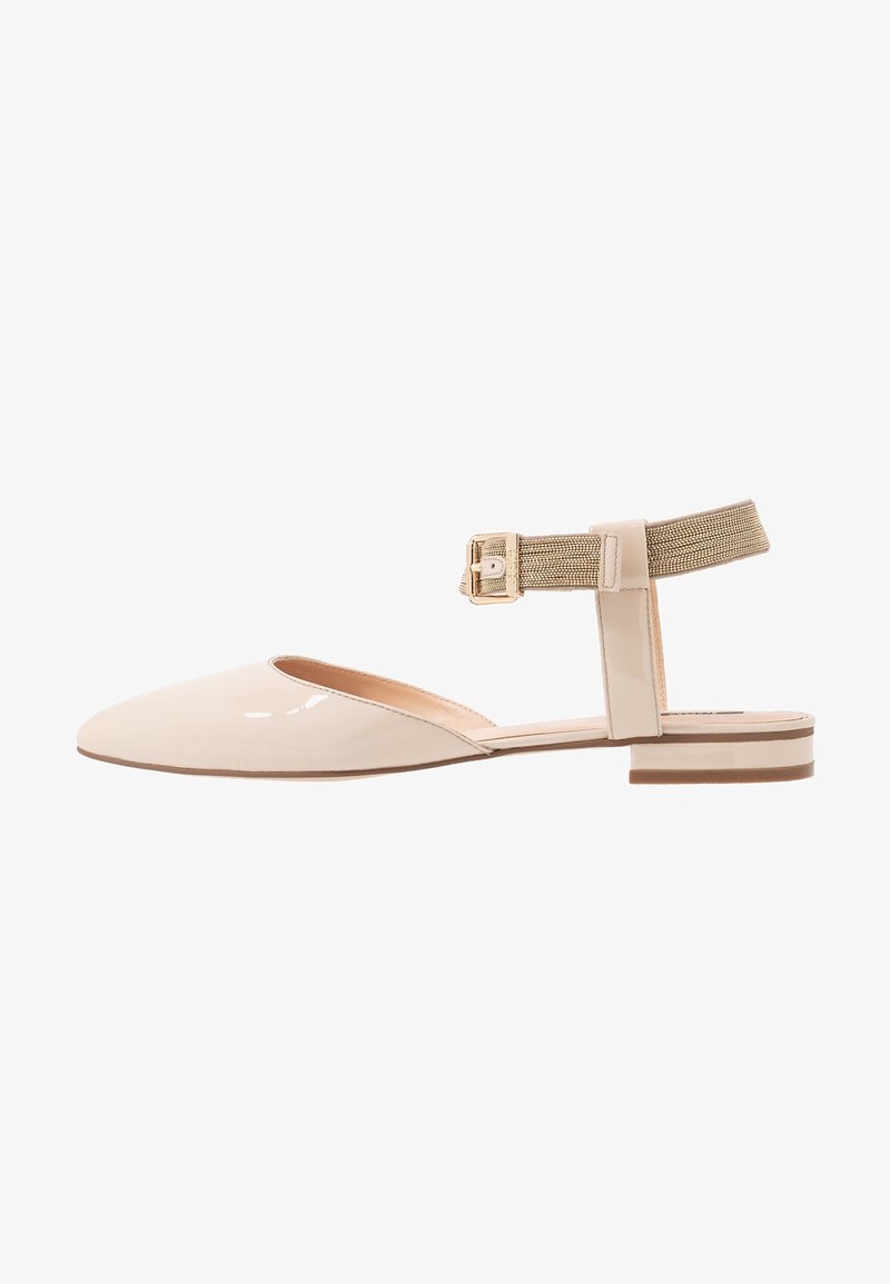 Chaussure plate en cuir verni beige avec bout pointu, bride élastique à la cheville et fermeture boucle dorée.