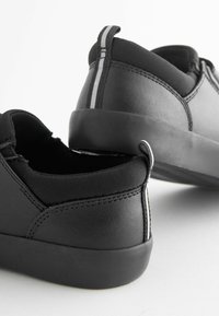 Zwarte schoenen met een glad leren bovenwerk en textiele accenten, een laag profiel ontwerp en een rubberen zool. Verticale streep details aan de achterkant.