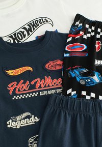 Trzy ubrania: białe i granatowe koszulki z logo Hot Wheels oraz czarne szorty z grafiką samochodową i w kratę.