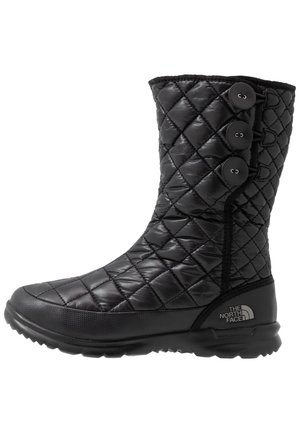 Botte d'hiver matelassée noire mi-mollet avec trois boutons sur le côté et une semelle texturée, avec le logo The North Face près du talon.