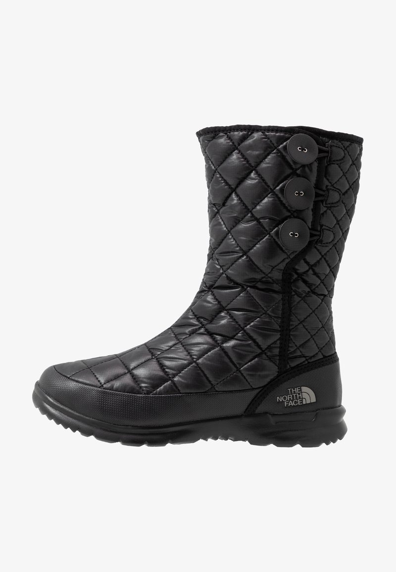 Botte d'hiver matelassée noire mi-mollet avec trois boutons sur le côté et une semelle texturée, avec le logo The North Face près du talon.