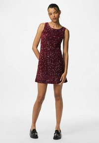 Burgundska haljina sa šljokicama bez rukava, s okruglim izrezom i opuštenim krojem, uparenom s crnim loafericama.