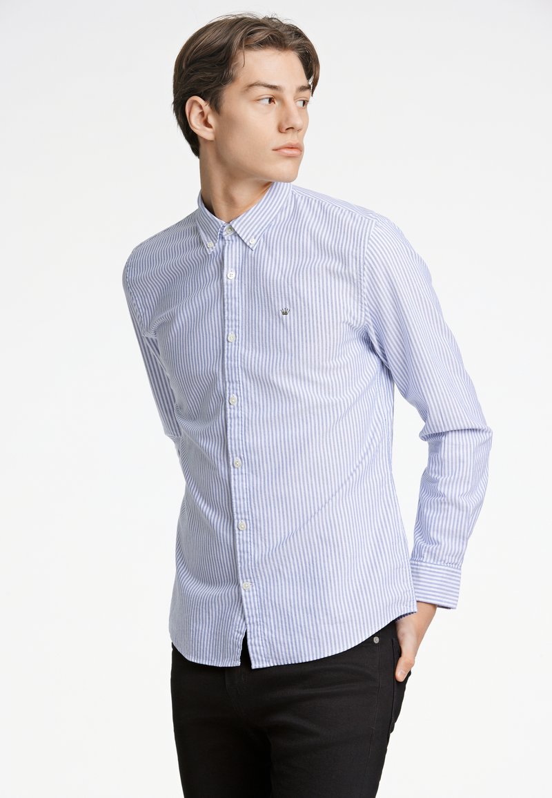 Camicia button-up in cotone leggero, con righe verticali blu e bianche. Include colletto, maniche lunghe e un piccolo logo sul petto.