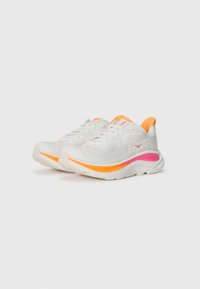 Baskets de sport blanches avec des accents roses et orange, présentant une surface texturée, une languette rembourrée et une semelle amortissante pour le confort.