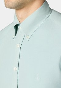 Lichtblauw button-up overhemd van katoen, met een klein geborduurd ontwerp op de linkerborst en een klassieke kraag met knopen.