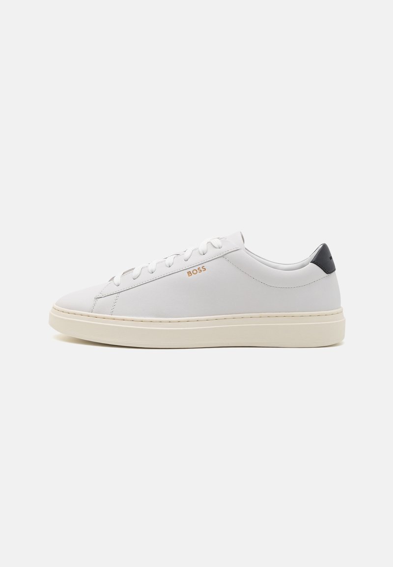Baskets basses blanches avec semelle beige, fermeture à lacets, languette de talon noire et logo doré "BOSS" sur le côté sur fond uni.