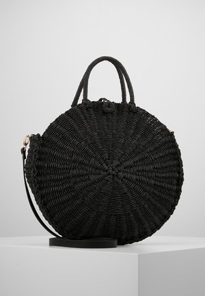 Czarna okrągła pleciona torebka z podwójnymi krótkimi uchwytami i odpinanym paskiem na ramię, wyeksponowana na białym piedestale na jednolitym tle.