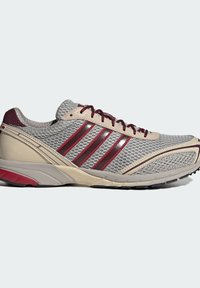 Γκρι αθλητικό παπούτσι με δίχτυ και μπεζ  σουέντ, με σκουροκόκκινες ρίγες, κορδόνια και λεπτομέρειες, διαθέτοντας μαξιλαρωμένη σόλα και υφή για καλύτερη πρόσφυση.