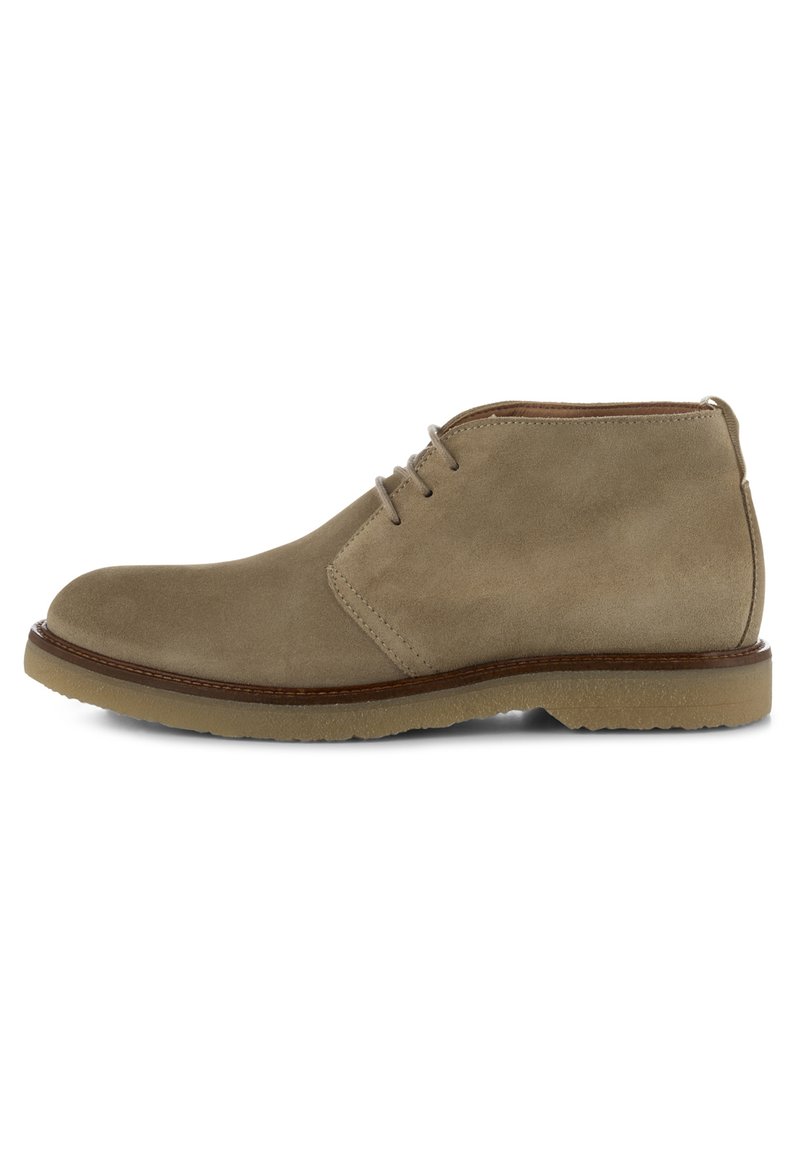 Stivaletto alla caviglia in suede beige con punta arrotondata, lacci a due occhielli, rifiniture in cuoio marrone e suola in gomma testurizzata.