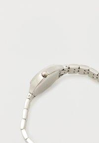 Silver watch with a rectangular case, metal link bracelet, polished finish, and a crown on the side; sleek design with a minimalist appearance.