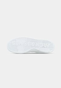 White sneaker sole featuring textured rubber with a zigzag pattern and molded branding details, designed for traction and stability.