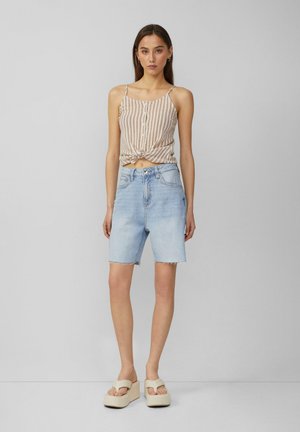 Shorts di denim azzurro con orlo sfrangiato, abbinati a un top corto a righe beige e bianche con bottoni e dettaglio a nodo.