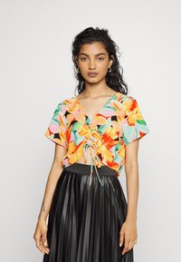 Top cropped floral com um padrão misto de laranja, rosa e verde sobre um fundo preto; apresenta um cordão na frente e mangas curtas.