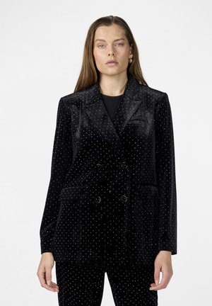 Blazer doppiopetto in velluto nero con pois bianchi, dotato di due tasche anteriori e collo a risvolto. Texture liscia e finitura lucida.