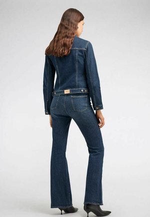 Giacca di jeans e jeans a zampa in blu scuro. La giacca presenta chiusure con bottoni, tasche laterali e dettagli di cucitura. Tessuto liscio, vestibilità su misura.