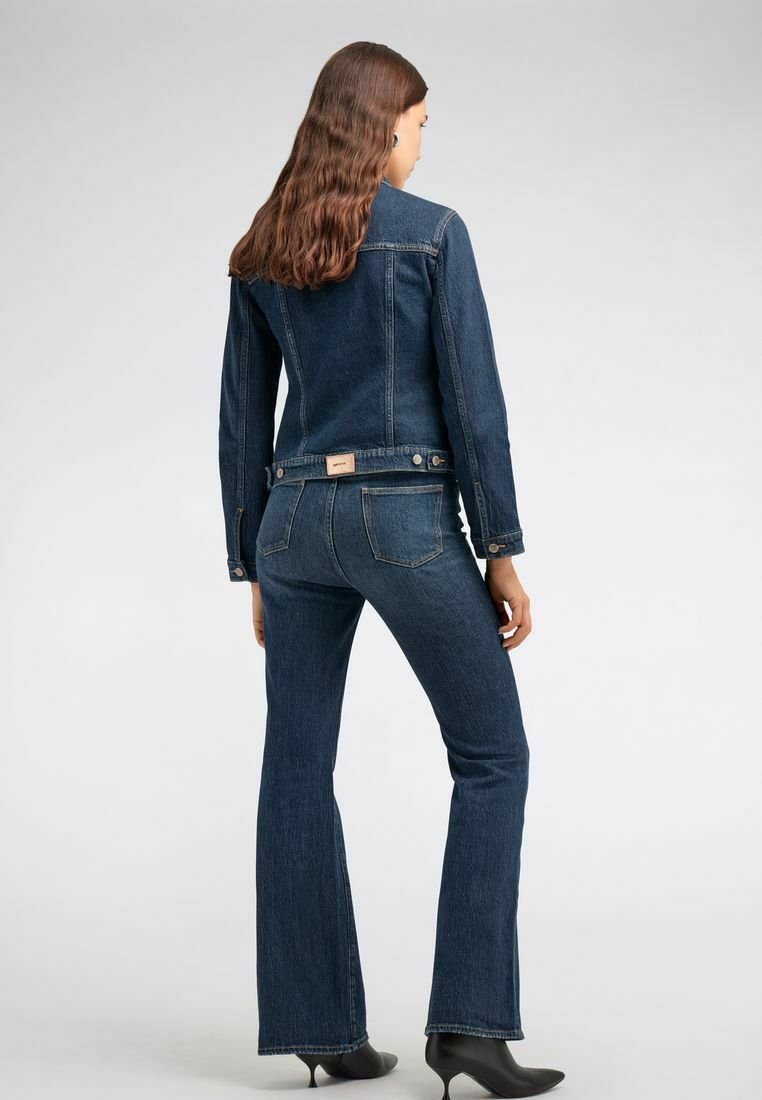 Chaqueta de mezclilla y jeans acampanados en azul oscuro. La chaqueta cuenta con cierres de botones, bolsillos laterales y detalles de costura. Textura suave y corte entallado.