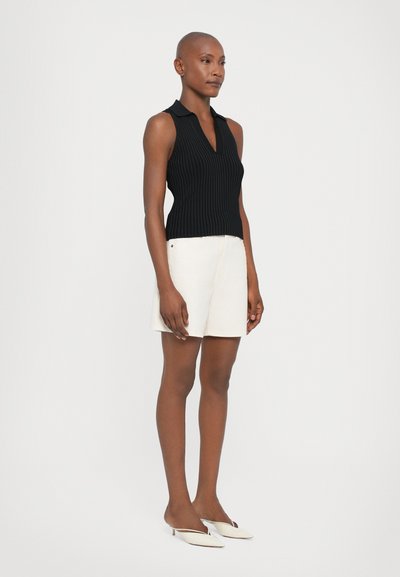 Black ribbed sleeveless polo top paired with off-white shorts and white pointed-toe shoes. Simple design, fitted silhouette, and smooth textures.