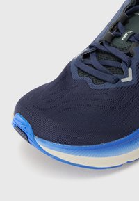 Scarpa sportiva blu navy con tomaia in mesh testurizzato, suola ammortizzata con accenti blu e lacci per una vestibilità sicura.