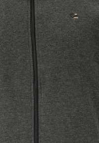 Grå zip-hoodie lavet af blødt stof, med en frontlynlås, detalje med et lille logo og en struktureret overflade.