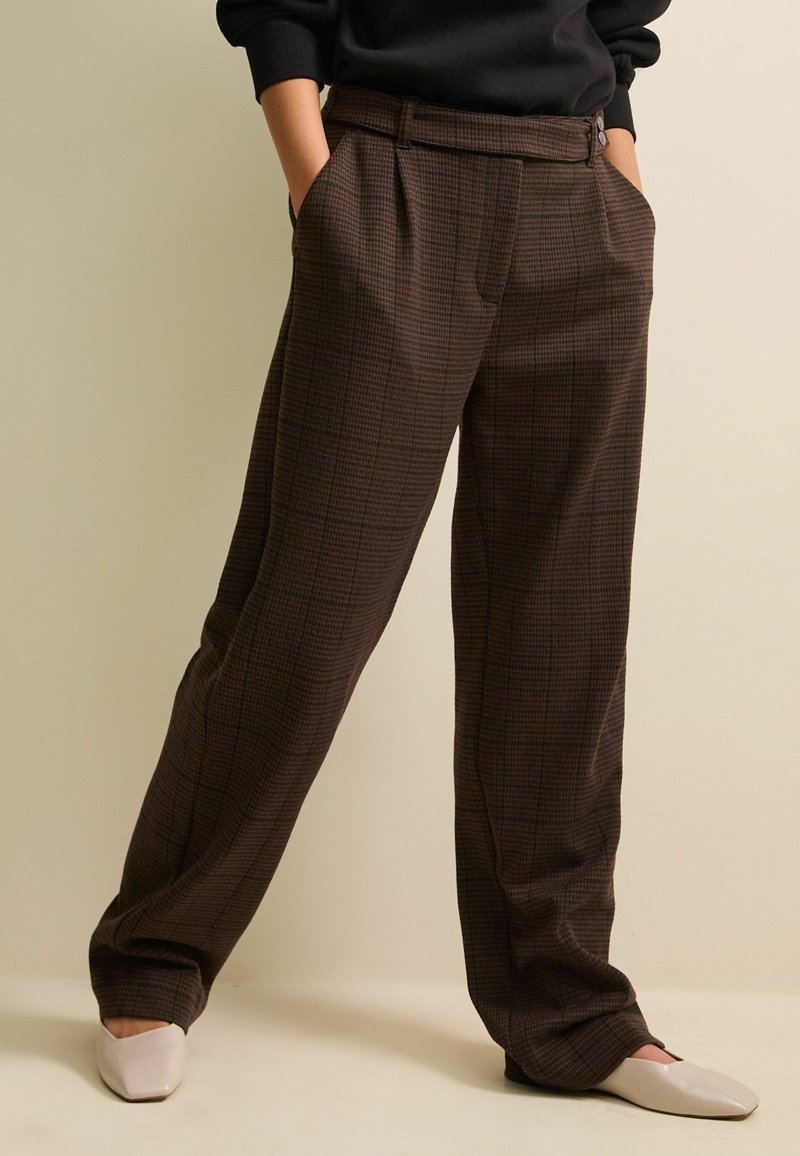 Pantaloni alti a scacchi marroni con una vestibilità rilassata, dotati di tasche laterali e una texture del tessuto liscia. Ben stirati con pieghe sottili.