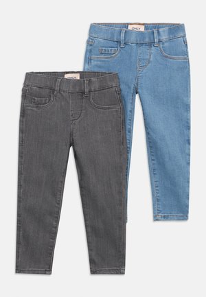 Twee paar kinderjassen, één donkergrijs en één lichtblauw, beide met voor- en achterzakken, riemlussen en merklabels in de taille.