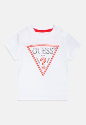 Vit t-shirt med kort ärm, med en röd och grå triangulär logotyp som har "GUESS" och ett frågetecken, tillverkad av mjukt bomullstyg.