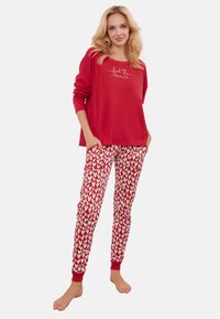 Czerwona bluza z napisem "poczuj miłość", w zestawie z czerwonymi spodniami z białym wzorem serc i elastycznymi mankietami. Miękki, casualowy materiał.