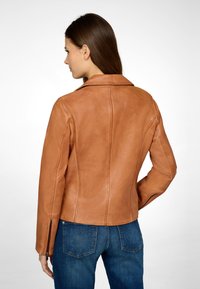 Bruine leren jacket met een slim fit ontwerp, scherpe kraag en ritsmanchetten, aangevuld met subtiele stikseldetails en een soepele textuur.