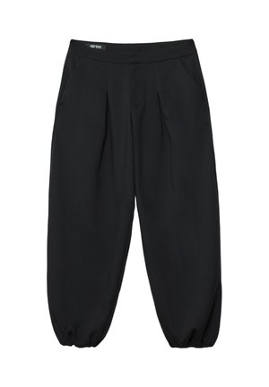 Personne portant un blazer oversize gris foncé, un crop top rayé noir et gris, un pantalon large noir et des bottes à plateforme noires à lacets.