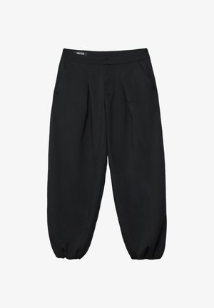 Osoba nosząca ciemnoszary oversize’owy blezer, czarno-szary paskowany crop top, szerokie czarne spodnie oraz czarne platformowe botki na sznurowadła.