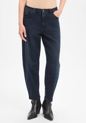 Dark blue denim jeans with a relaxed fit, mid-rise waist, front pockets, and black pointed-toe heeled ankle boots.