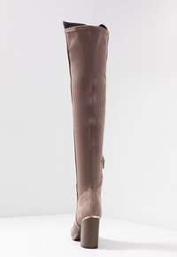 Botas marrones hasta la rodilla hechas de cuero liso con un tacón de ante texturizado, que cuentan con una cremallera lateral y un diseño de punta redonda.