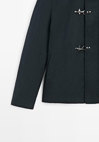 Manica di cappotto in blu navy scuro con due chiusure a fibbia argentate e una tasca laterale verticale sul davanti.