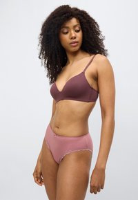 Soutien-gorge mauve foncé avec bretelles fines et décolleté plongeant, associé à un shorty assorti rose avec bordure en dentelle et détail nœud.