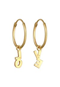 Paire de boucles d'oreilles créoles en or avec des lettres pendantes "L" et "E" dans un style moderne et géométrique sur fond blanc.
