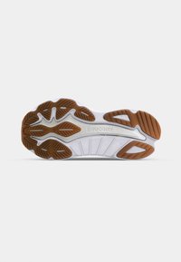 Bílá podrážka běžecké boty s texturovaným gumovým povrchem. Obsahuje hnědé prvky pro trakci a drážky pro flexibilitu. Logo "Saucony" je viditelné.