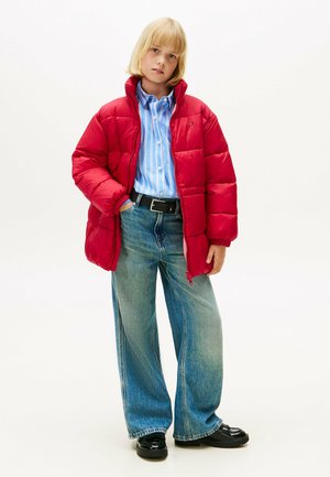 Rode pufferjack met hoge kraag, blauw-wit gestreept shirt, lichtblauwe spijkerbroek en zwarte schoenen. Casual outfit met een relaxte pasvorm.