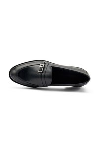 Mocassino in pelle nera con punta arrotondata, caratterizzato da una fascia prominente e un dettaglio di fibbia rettangolare in argento. Texture liscia, design minimal.