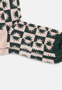 Bomullssockar med ett rutigt mönster i grön och kräm, dekorerade med stjärnformer; märkta med "DillySocks" i vit text.