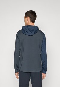 Long-sleeve hoodie in dark gray with a contrasting navy hood. Smooth texture, relaxed fit, and tapered cuffs with a low back hem.