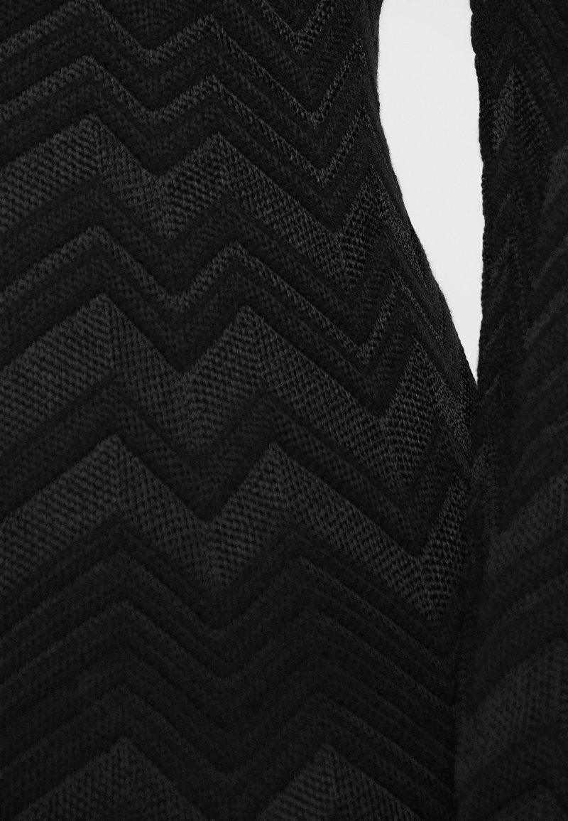 Tissu noir texturé présentant un motif en chevrons avec des lignes en relief, créant de la profondeur et un intérêt visuel dans un design répétitif.