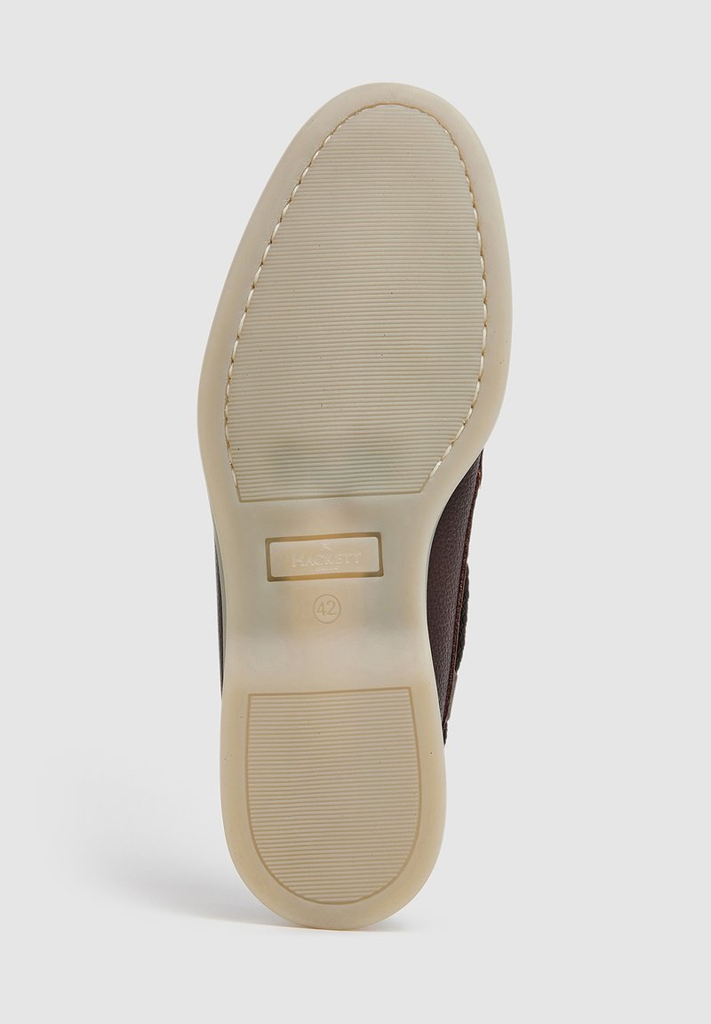Semelle d'une chaussure en cuir brun avec une semelle extérieure en caoutchouc beige, présentant une texture antidérapante, des détails de couture et le logo embossé "Hackett London" ainsi que la taille 42.