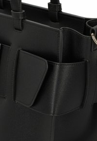 Zwarte leren tas met een gestructureerd ontwerp, een textuurafwerking en een buitenvak met een klepsluiting. Gekleed met duurzame draagriemen.