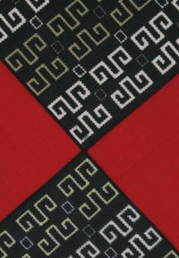 Textile featuring a geometric pattern in black, white, and gold, contrasted with solid red sections, showcasing varied textures and designs.
