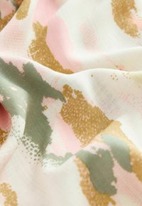 Abstract fabric with a white background, featuring irregular patterns in pink, gold, and muted green tones. Smooth texture, lightweight material.