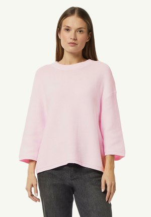 Light pink knitted sweater with a round neckline, three-quarter sleeves, and an asymmetrical hem. Textured fabric with ribbed accents.