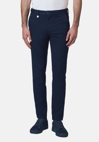 Granatowe chinosy o dopasowanym kroju, wykonane z materiału bawełnianego. Posiadają szlufki na pasek, kieszenie z przodu oraz zapięcie na guzik.