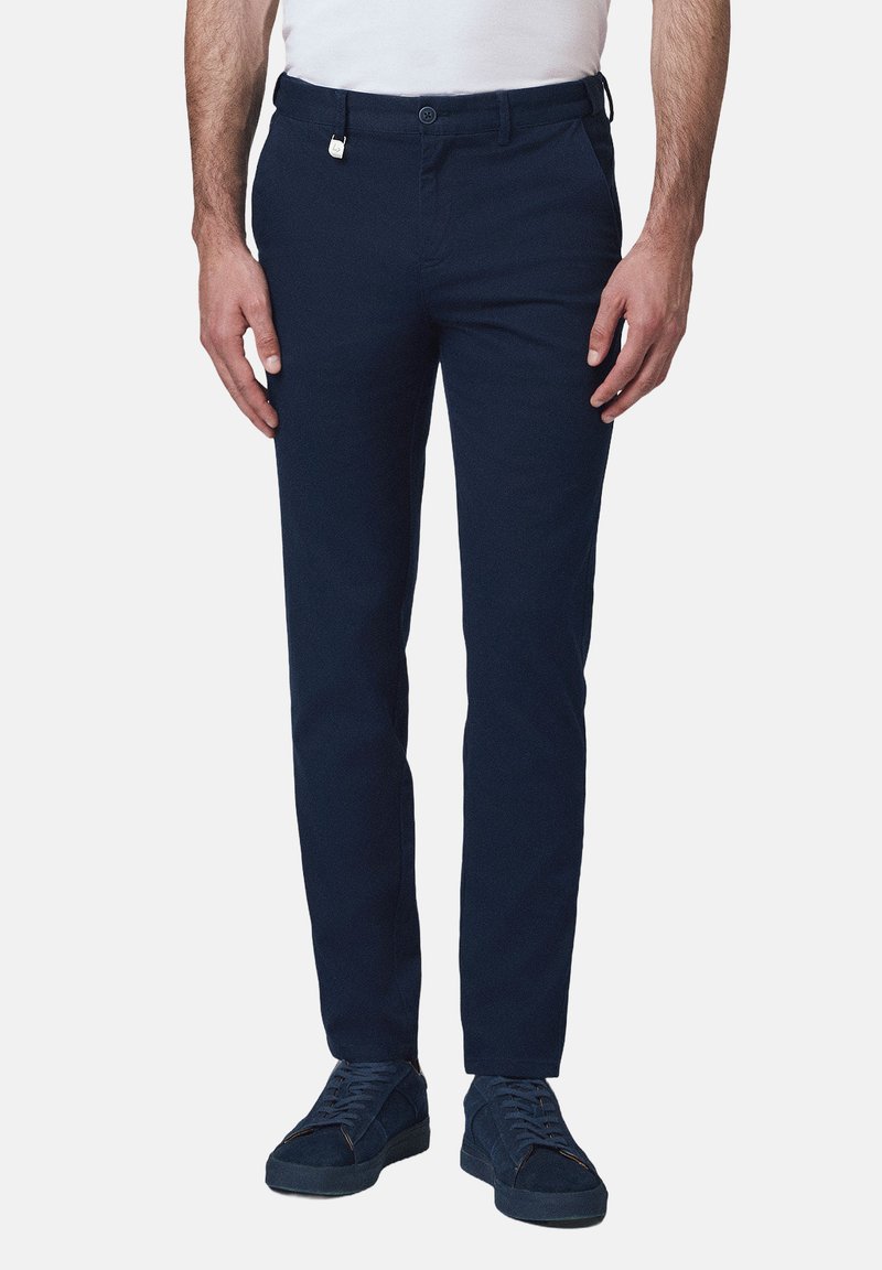Granatowe chinosy o dopasowanym kroju, wykonane z materiału bawełnianego. Posiadają szlufki na pasek, kieszenie z przodu oraz zapięcie na guzik.