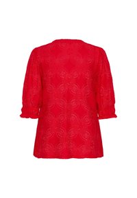 Blusa rossa in pizzo con maniche corte a sbuffo e un motivo floreale. Il tessuto è strutturato e presenta un orlo scallopato nella parte inferiore.
